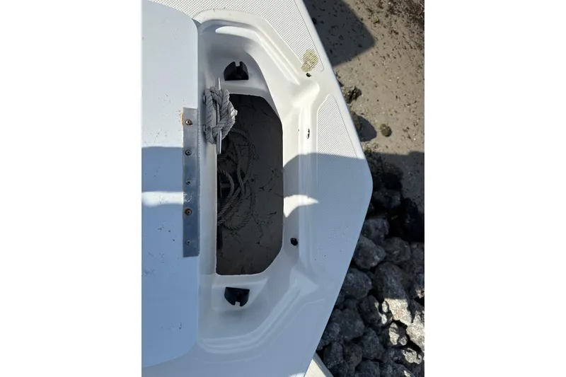 Slide: The Image of 2018 Hurricane SunDeck 2486 OB boat anchor storage compartment with rope, on sandy shore. - 59