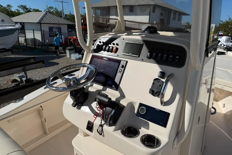 Slide: The Image of 2024 Grady-White 231 Coastal Explorer boat dashboard with steering wheel and controls. - 7