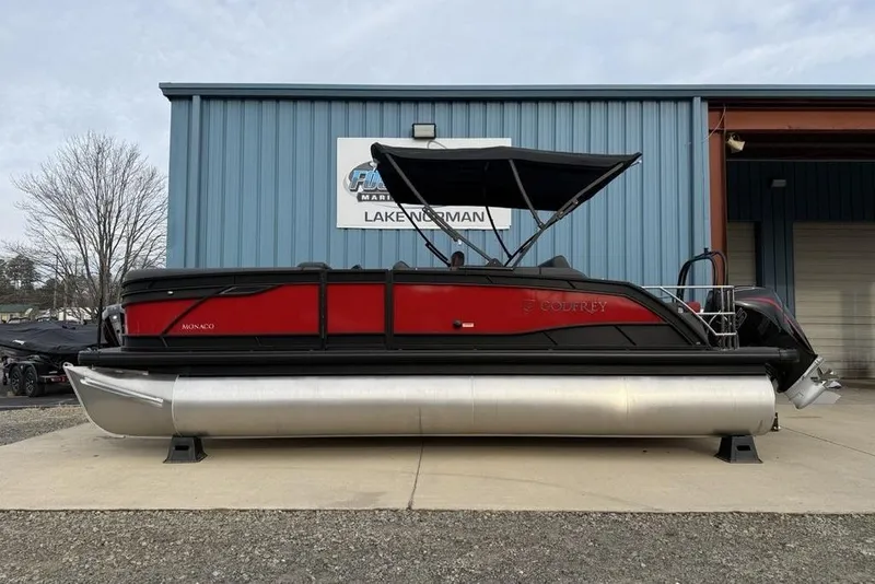 The Image of 2026 Godfrey Monaco 235 SFL pontoon boat with red and black design, docked at marina. - 0