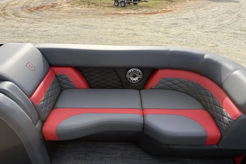 Slide: The Image of 2026 Godfrey Monaco 235 SFL pontoon boat with outboard motor, parked near a blue building. - 3