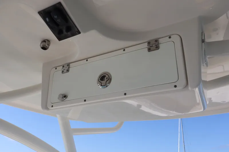 Slide: The Image of 2017 Sailfish 320 CC boat storage compartment with latch and hinges, viewed from below. - 18