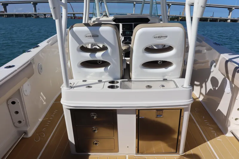 Slide: The Image of 2017 Sailfish 320 CC boat interior with dual seats and storage, docked near a bridge. - 20