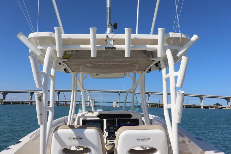 Slide: The Image of 2017 Sailfish 320 CC boat on water, featuring helm and rod holders, with bridge in background. - 21