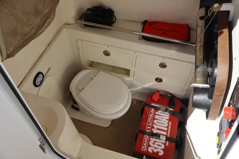 Slide: The Image of 2017 Sailfish 320 CC boat interior with marine toilet and emergency kit. - 28