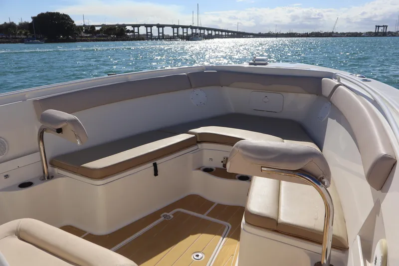 Slide: The Image of 2017 Sailfish 320 CC boat interior with cushioned seating, on a sunny day by the water. - 5