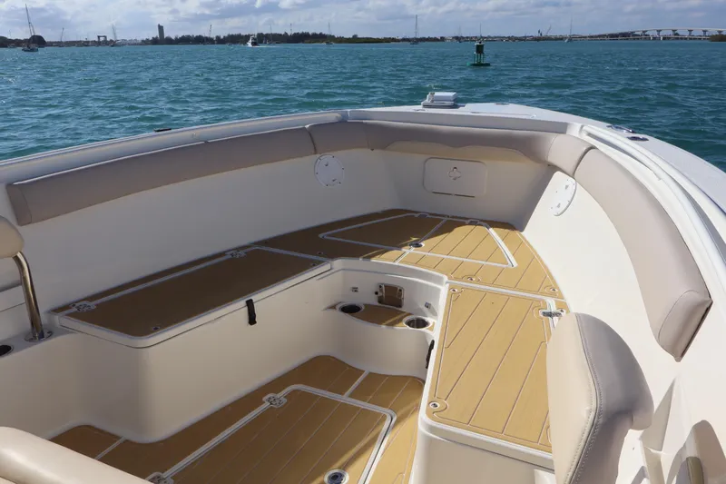 Slide: The Image of 2017 Sailfish 320 CC boat interior with cushioned seating and wooden deck, on calm water. - 7