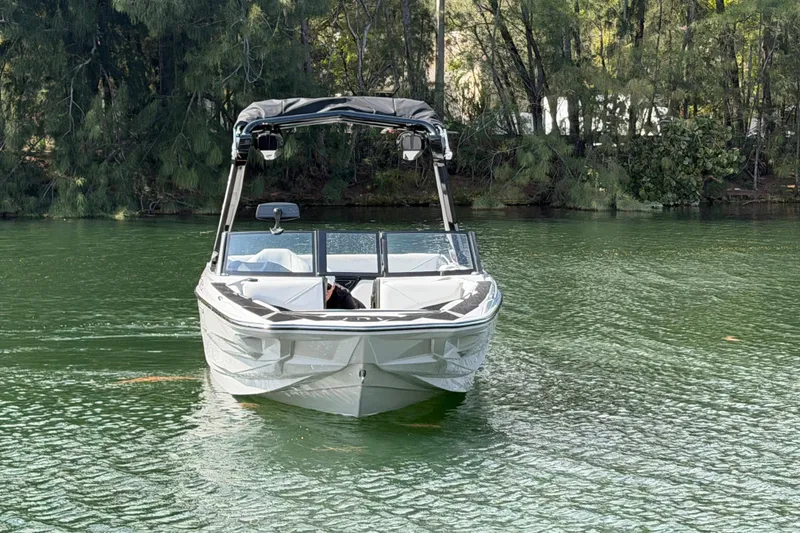 Slide: The Image of 2026 Centurion Nv233 boat on a serene lake with lush forest backdrop. - 25