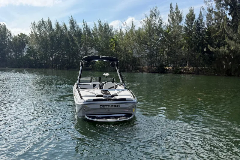 Slide: The Image of 2026 Centurion Nv233 boat on a serene lake with lush trees in the background. - 28