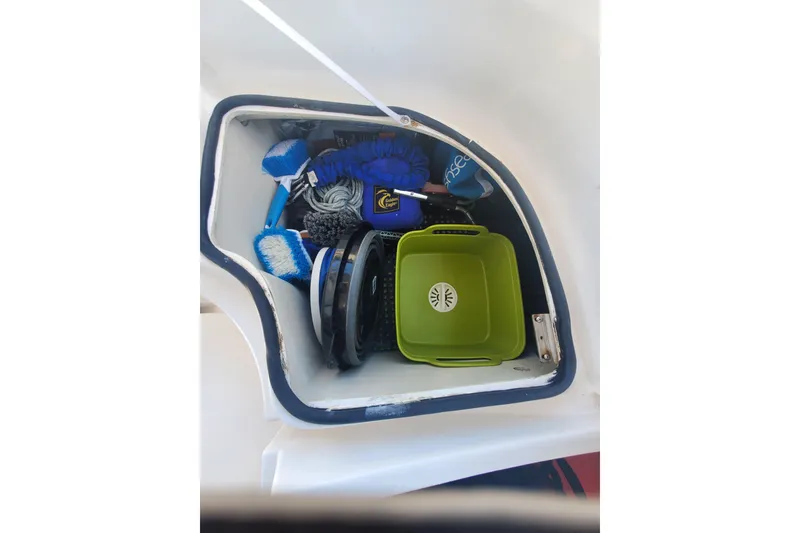 Slide: The Image of Storage compartment on a 2003 Hunter 426 Deck Salon, containing cleaning supplies and a green tray. - 38