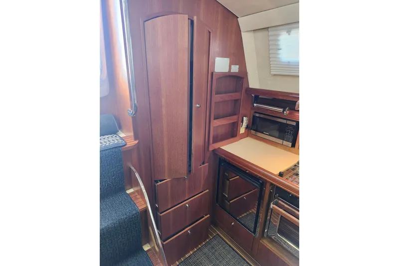 Slide: The Image of Interior of 2003 Hunter 426 Deck Salon, featuring wooden cabinetry and kitchen appliances. - 49