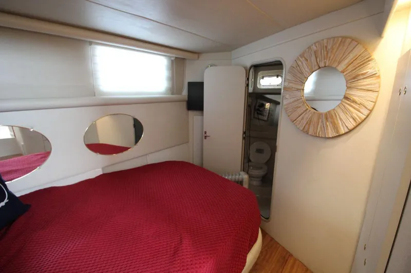 Slide: The Image of 1997 Cruisers Yachts 3650 Motoryacht bedroom with red bedding and circular mirror. - 26