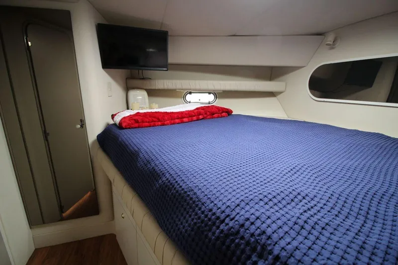 Slide: The Image of 1997 Cruisers Yachts 3650 Motoryacht bedroom with blue bedding and wall-mounted TV. - 31