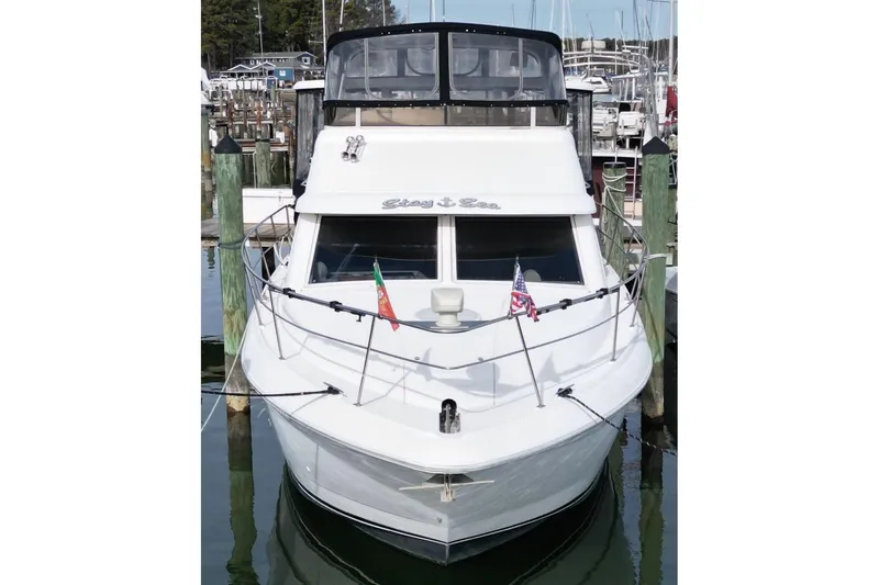 Slide: The Image of 1997 Cruisers Yachts 3650 Motoryacht docked, front view with flags displayed. - 6