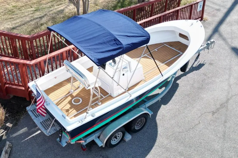 The Image of 1979 Shamrock 200 Stalker boat with blue canopy on trailer, wooden deck, and American flag. - 0