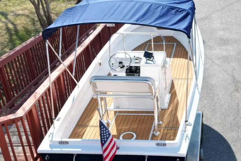 Slide: The Image of 1979 Shamrock 200 Stalker boat with blue canopy and wooden deck, docked near a red railing. - 3
