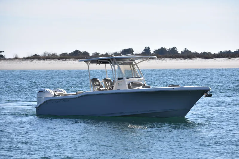 The Image of 2024 Key West 263 FS boat cruising on calm blue waters near a sandy shoreline. - 0