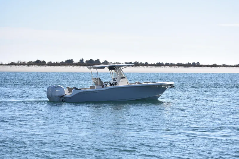 Slide: The Image of 2024 Key West 263 FS boat cruising on calm blue waters near a sandy shoreline. - 4