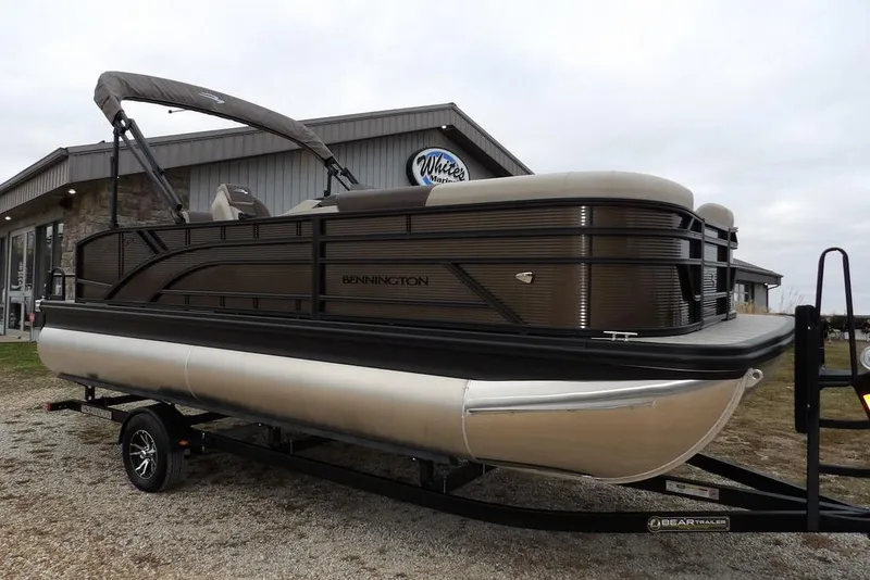 The Image of 2026 Bennington S Swingback 21 SSB pontoon boat on trailer, parked outside dealership. - 1