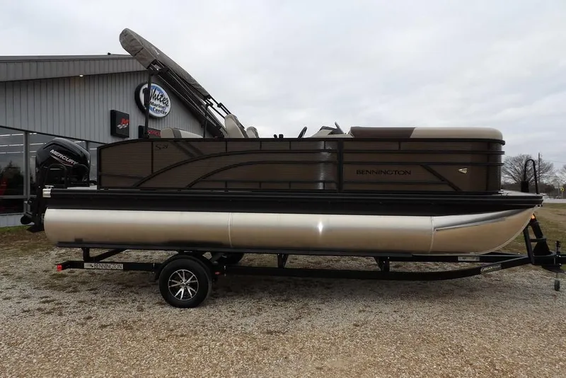 Slide: The Image of 2026 Bennington S Swingback 21 SSB pontoon boat on trailer, parked outside dealership. - 4
