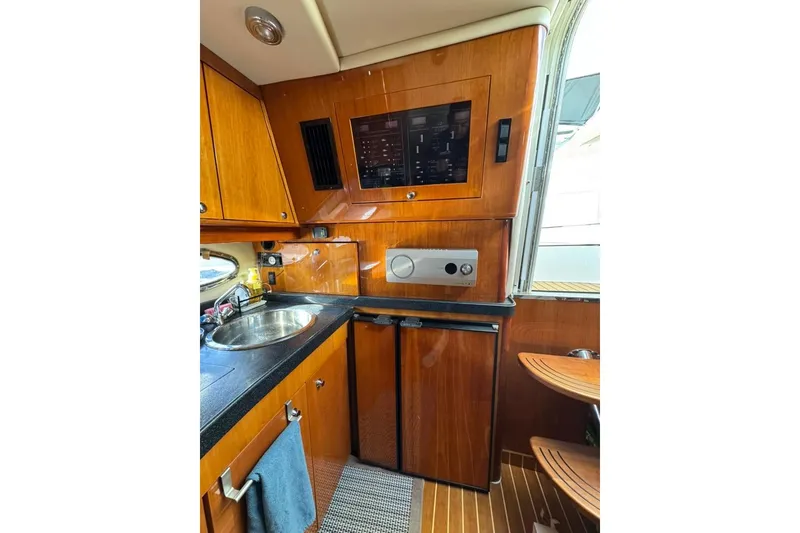 Slide: The Image of 2006 Regal Commodore 4460 yacht interior with wooden cabinetry, sink, and compact appliances. - 25