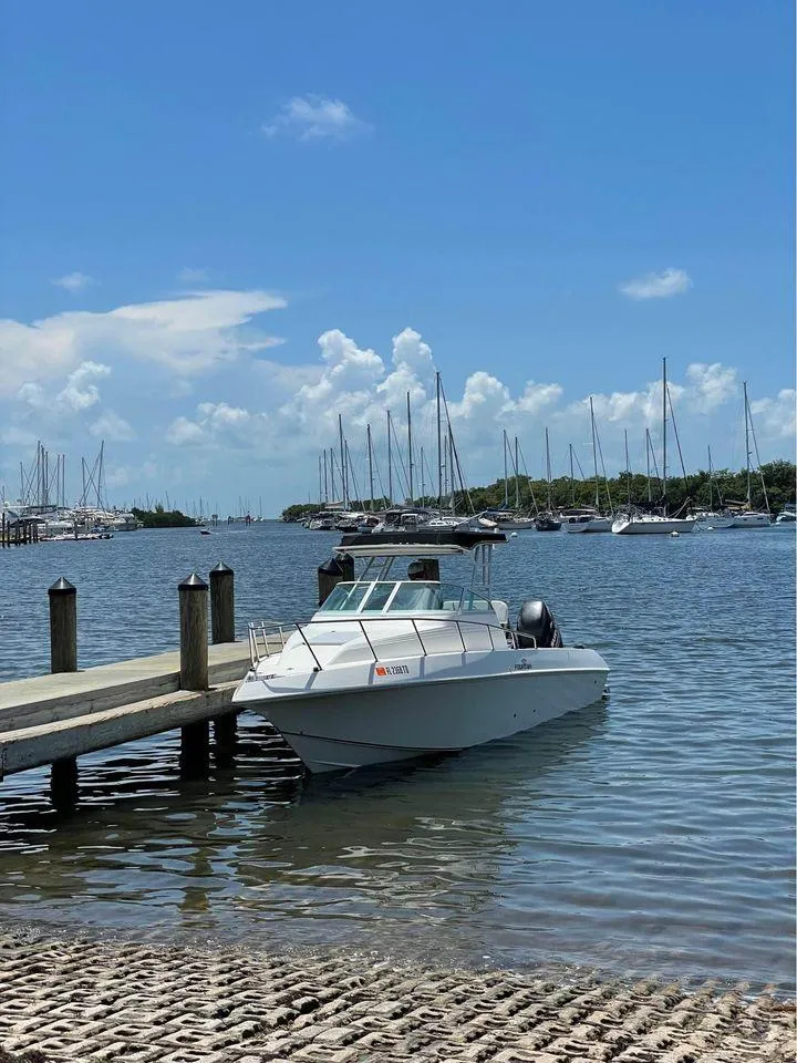 Slide: The Image of 1993 Fountain Walk Around boat docked by a pier, with sailboats in the background. - 3