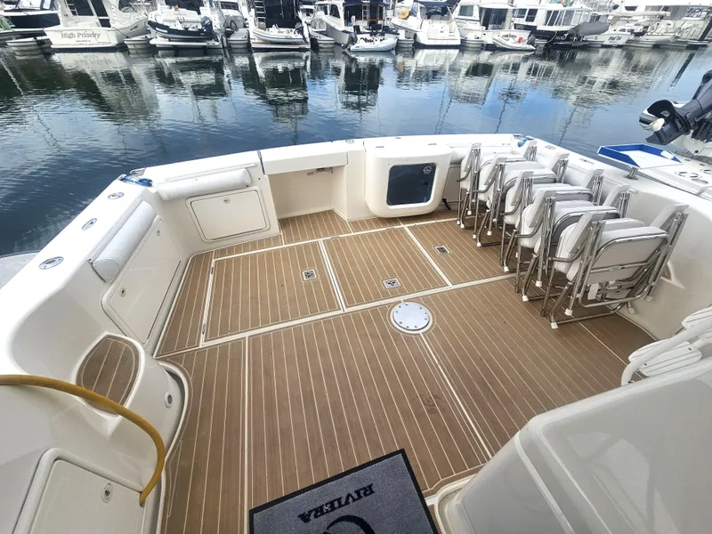 Slide: The Image of Riviera 42 Flybridge 2005, spacious deck with chairs in marina. - 12