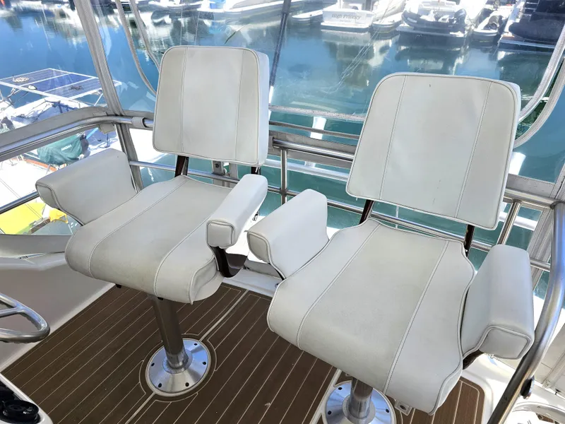Slide: The Image of Riviera 42 Flybridge 2005, white seats on boat, harbor background. - 7