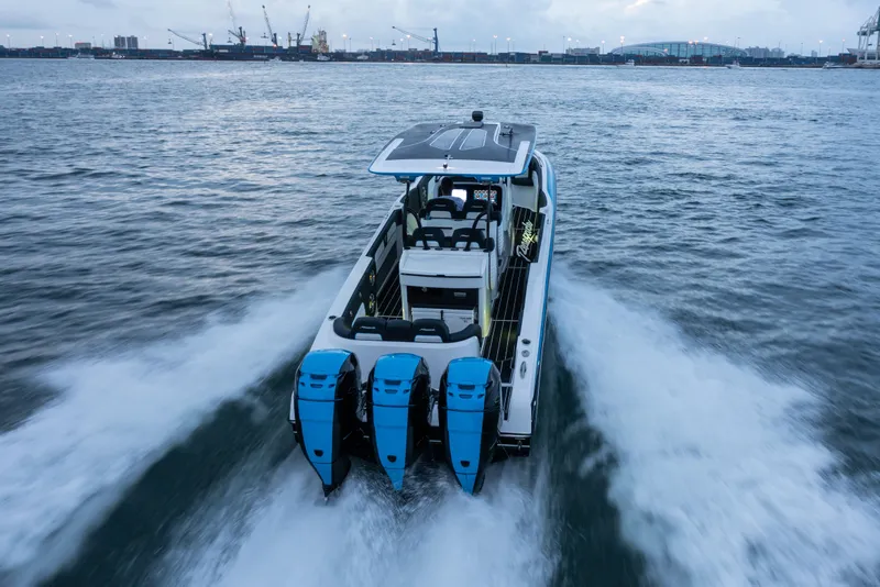 Slide: The Image of 2022 Renegade 38' Open boat cruising on water with triple outboard engines. - 7