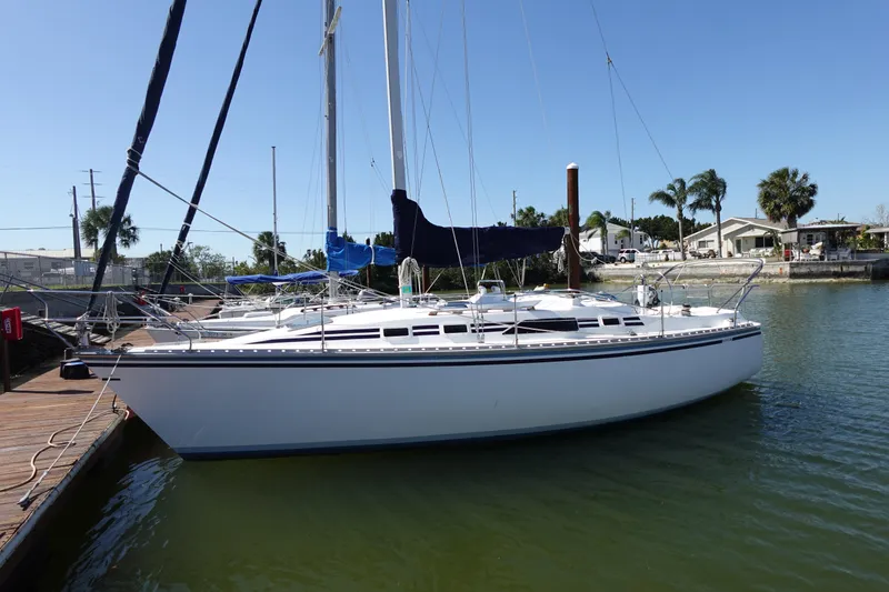 The Image of 1987 Hunter 310 sailboat docked in a sunny marina with palm trees. - 0