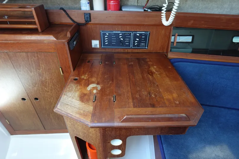 Slide: The Image of 1987 Hunter 310 sailboat interior with wooden navigation station and control panel. - 23