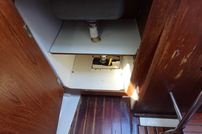 Slide: The Image of 1987 Hunter 310 interior sink area with wooden cabinetry and plumbing. - 28