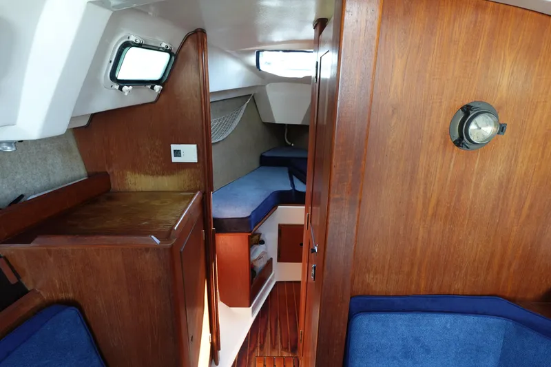 Slide: The Image of 1987 Hunter 310 sailboat interior with wood paneling and blue cushions. - 39