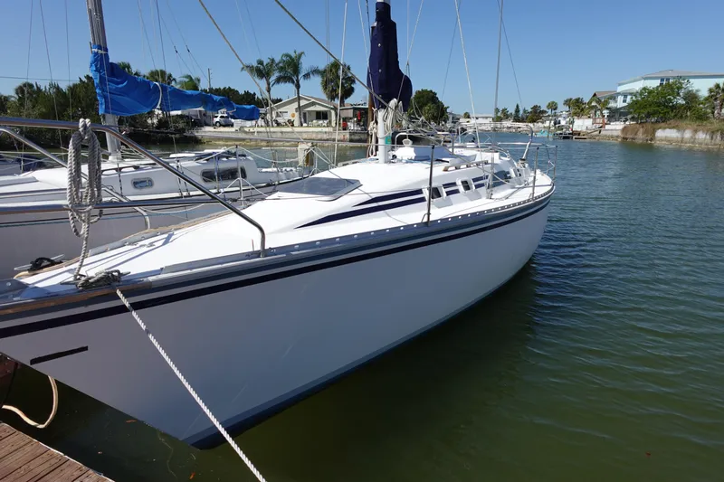 Slide: The Image of 1987 Hunter 310 sailboat docked in a marina, clear sky, calm water. - 4