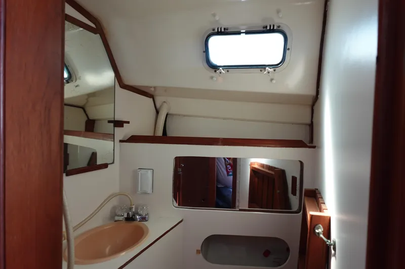 Slide: The Image of Interior of 1987 Hunter 310 sailboat bathroom with sink, mirror, and porthole window. - 44
