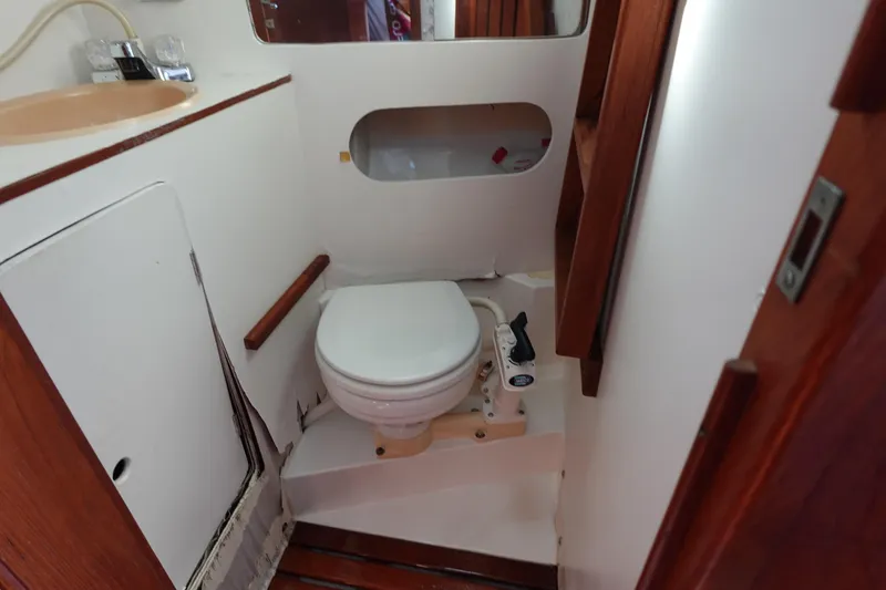Slide: The Image of 1987 Hunter 310 boat bathroom with toilet, sink, and wooden accents. - 46