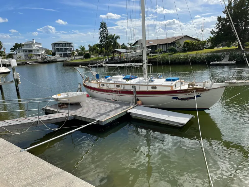 Slide: The Image of 1985 Tayana 37 Cutter sailboat docked in a serene marina setting. - 1