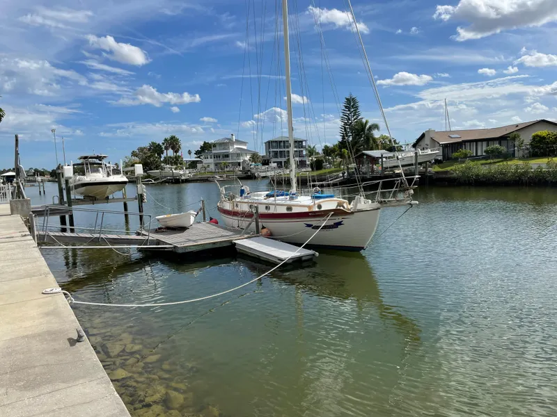 Slide: The Image of 1985 Tayana 37 Cutter sailboat docked in a serene marina under a blue sky. - 2