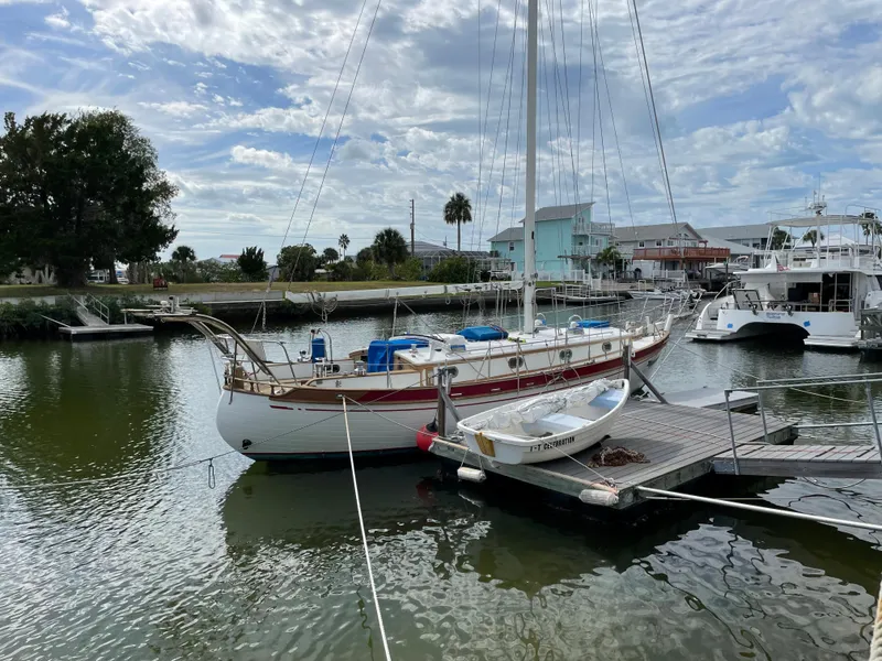 Slide: The Image of 1985 Tayana 37 Cutter sailboat docked in a marina under a cloudy sky. - 3