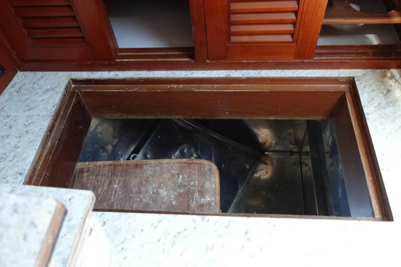 Slide: The Image of Open storage compartment on 1985 Tayana 37 Cutter sailboat, featuring wooden cabinetry and countertop. - 37