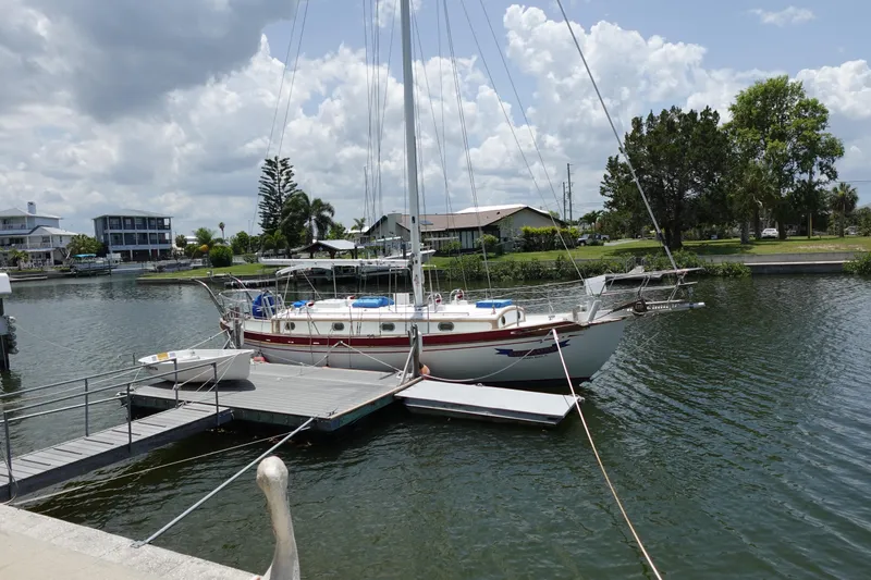 Slide: The Image of 1985 Tayana 37 Cutter sailboat docked in a serene marina setting. - 4