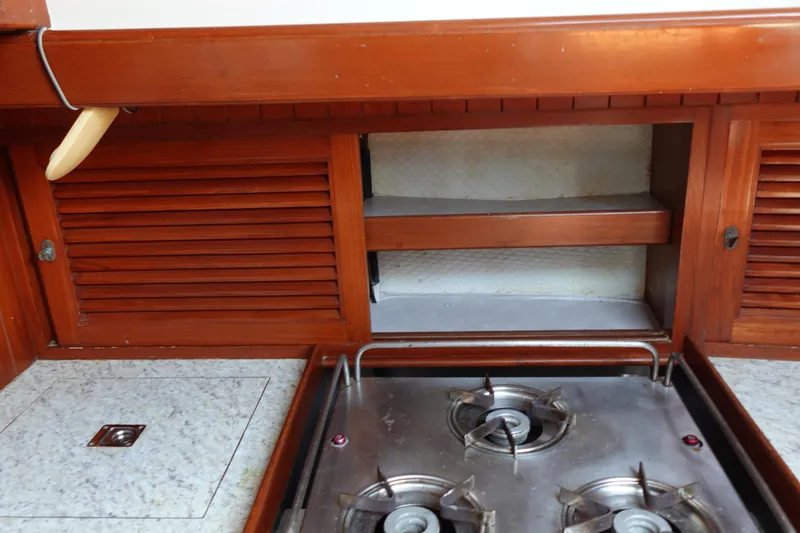 Slide: The Image of 1985 Tayana 37 Cutter yacht kitchen with wooden cabinets and a two-burner stove. - 42