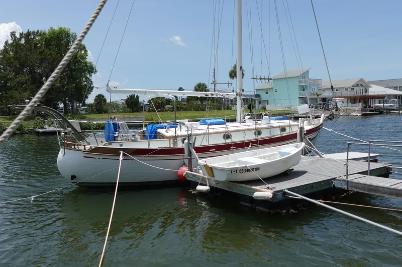 Slide: The Image of 1985 Tayana 37 Cutter sailboat docked at marina with small dinghy. - 6