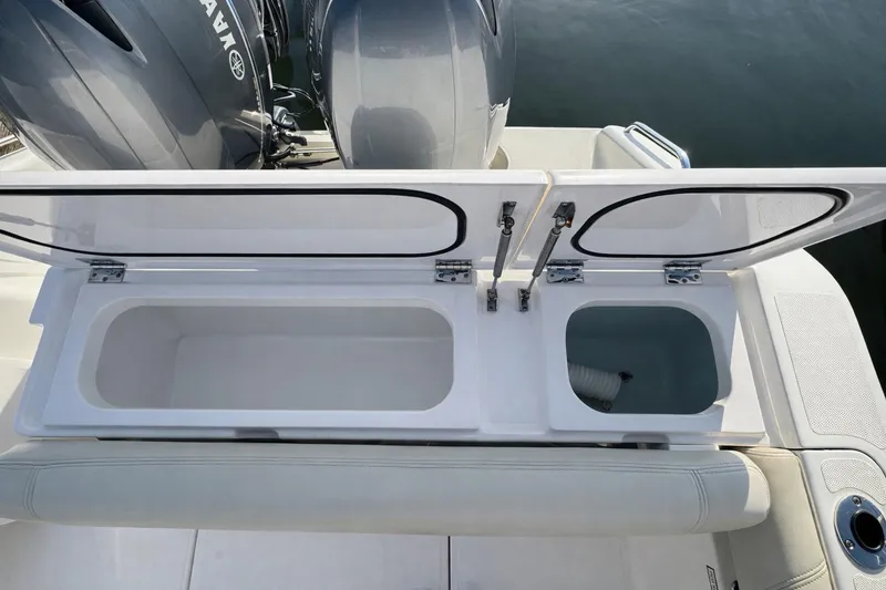 Slide: The Image of 2015 Pursuit DC 265 Dual Console boat interior with beige seating by the water. - 5