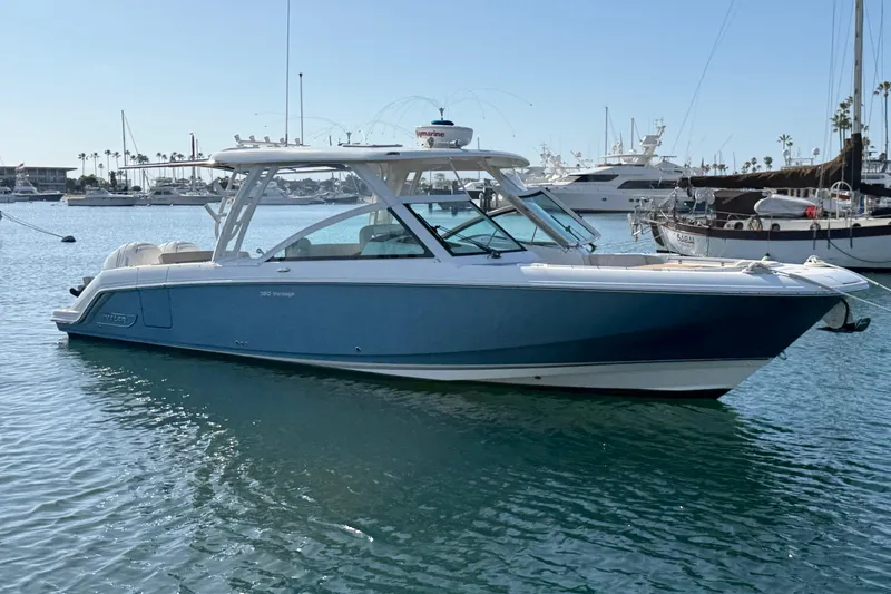 The Image of 2020 Boston Whaler 320 Vantage boat docked in a marina, surrounded by other vessels. - 0