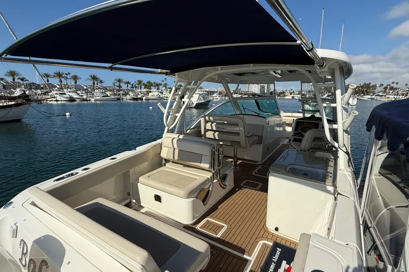 Slide: The Image of 2020 Boston Whaler 320 Vantage boat docked in a marina, featuring spacious seating and canopy. - 16