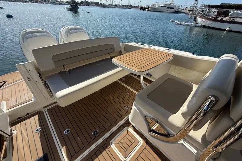 Slide: The Image of 2020 Boston Whaler 320 Vantage interior with cushioned seating and teak flooring, docked in marina. - 19