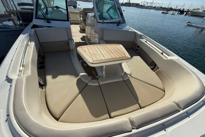 Slide: The Image of 2020 Boston Whaler 320 Vantage boat interior with cushioned seating and table, docked at marina. - 51