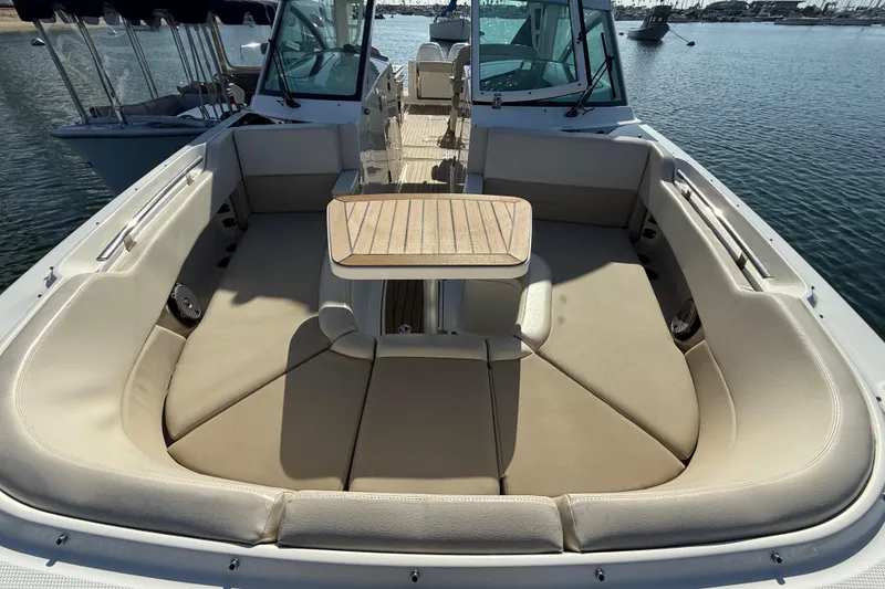 Slide: The Image of 2020 Boston Whaler 320 Vantage boat interior with cushioned seating and table on water. - 52