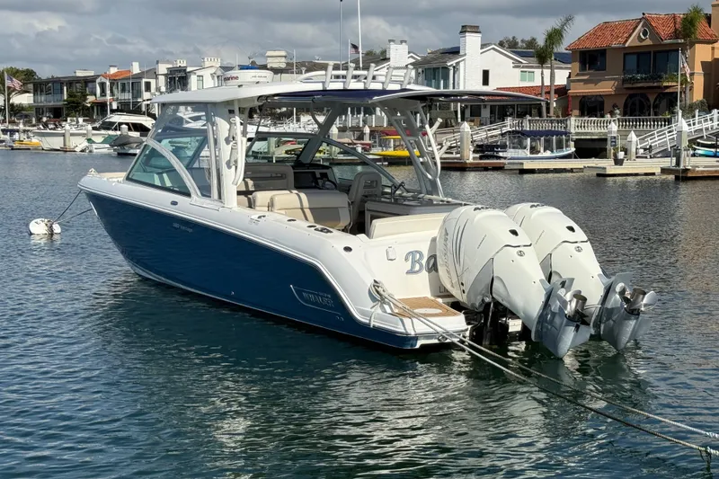 Slide: The Image of 2020 Boston Whaler 320 Vantage boat docked in a marina, featuring dual outboard engines. - 6