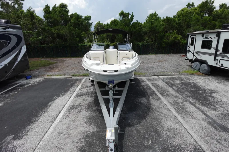 Slide: The Image of 2022 Stingray 231 DC boat on trailer in parking lot, surrounded by trees and RVs. - 12